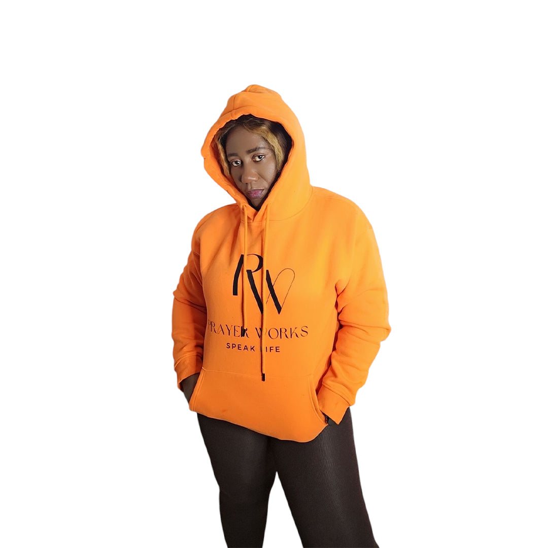 Prayer Work Speak Life Inspirational Unisex Hoodie in orange, worn by a person, featuring motivational text design.